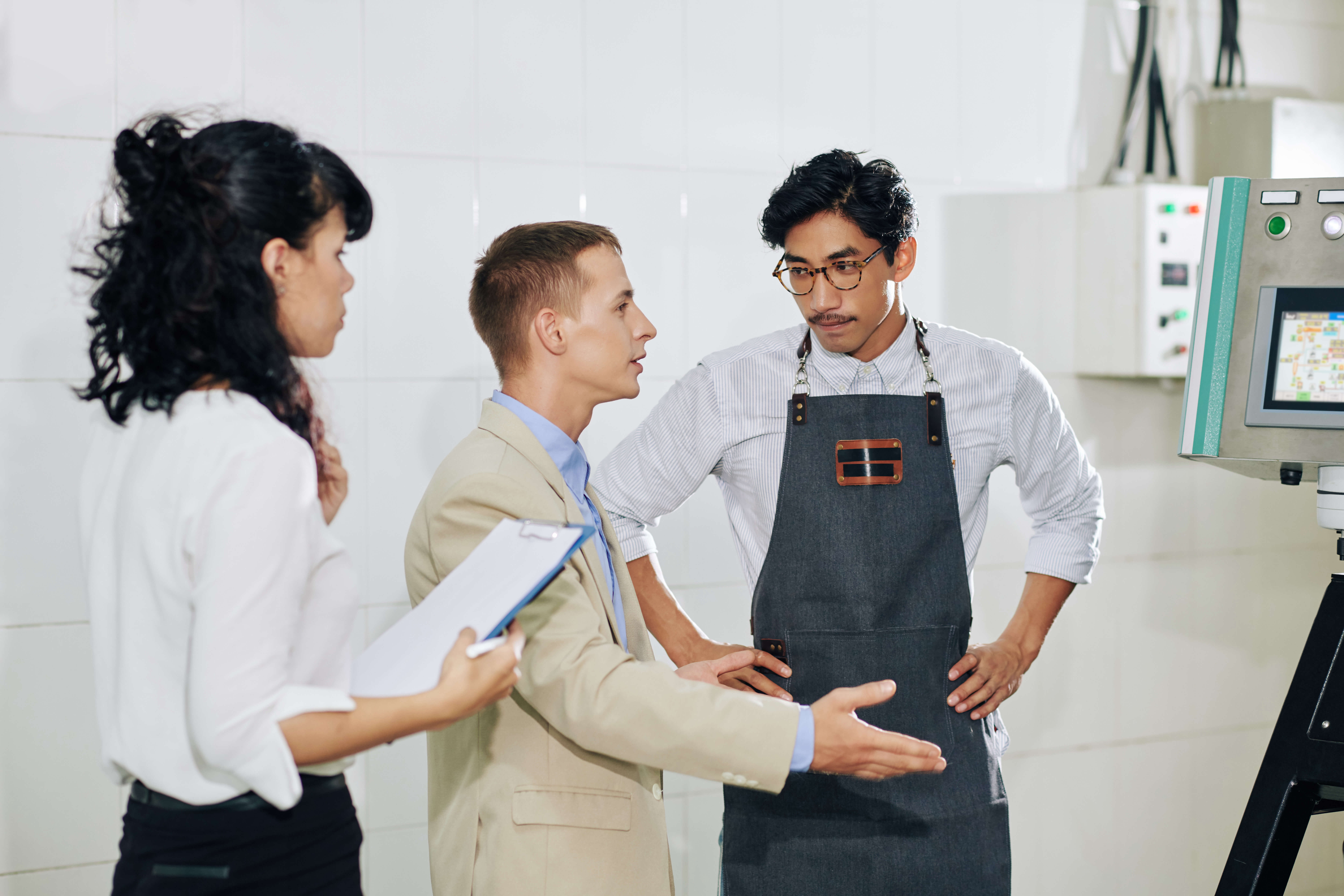 Small manufacture owner in apron talking to business partner and his assistant