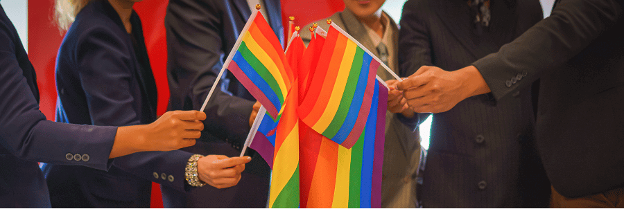 Group of colleagues holding LGBTQ Pride flags in the workplace