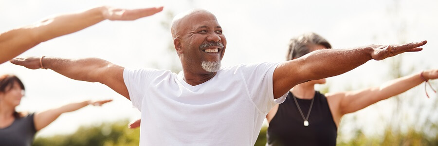 Group Of Mature Men And Women In Class At Outdoor Yoga