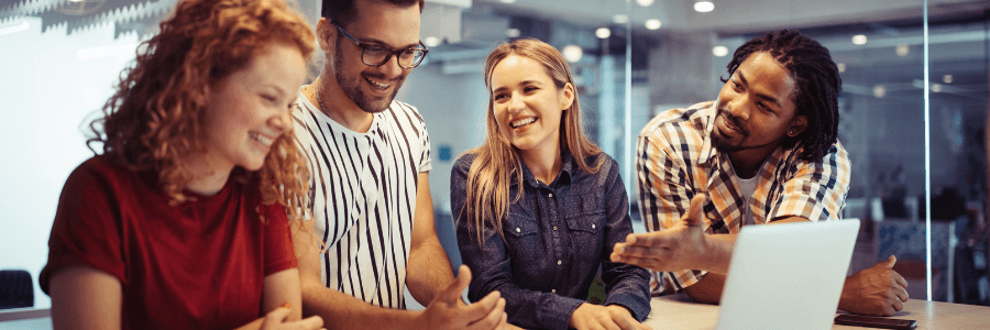 Happy, engaged employees gathering around a laptop