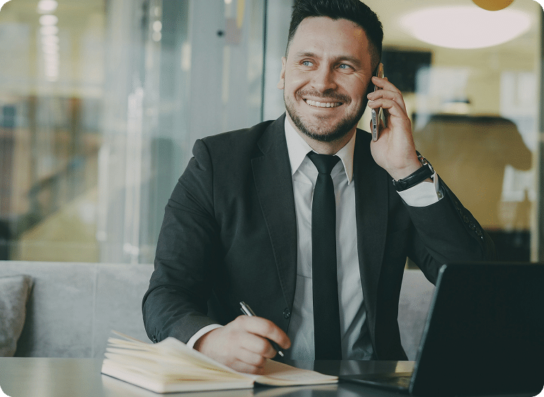 business man sitting at table smiling on phone