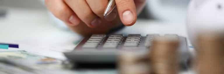 Male hand push key silver calculator is lying on desk cash dollar plots in home office setting. Calculation of family expenses social income population freelance irs situation growth research concept